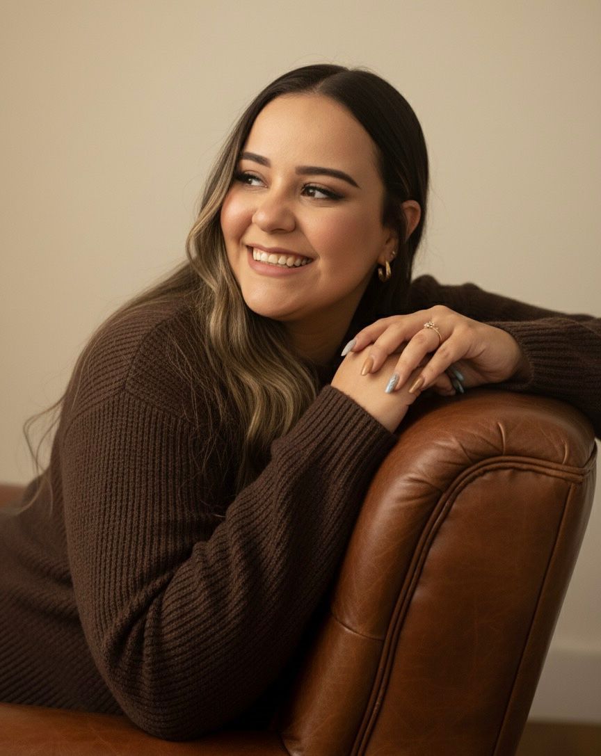 Retrato de Talita Freitas, psicanalista, sorrindo apoiada em uma poltrona de couro
